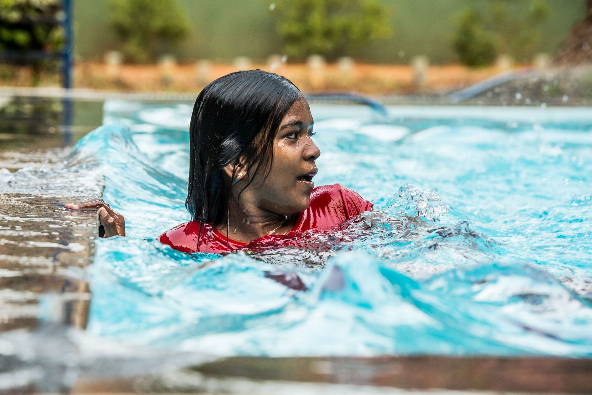 Kind hält sich am Beckenrand fest und übt Schwimmen im Pool des Angels Home