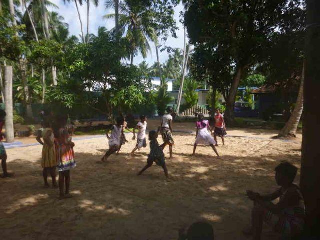 Man sieht ca. 10 Mädchen, die auf einem Volleyballfeld das Spiel Kaberti spielen.