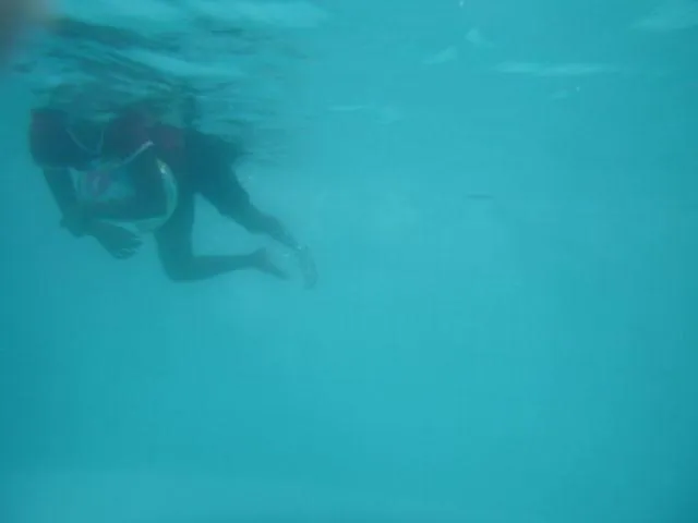 Das Bild wurde unter Wasser aufgenommen. Man sieht ein M&auml;dchen, das einen Wasserball als Schwimmhilfe benutzt