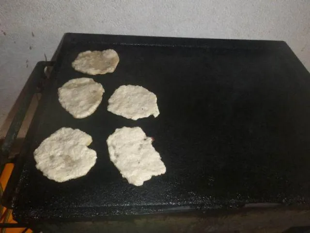Man sieht Roti-Pfannkuchen, die gerade angebraten werden.