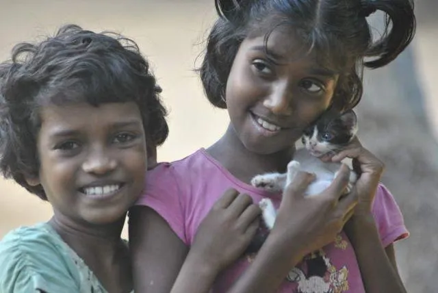 Man sieht Madushani und Achini mit einer kleinen Katze auf dem Arm