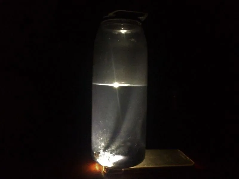 Eine Wasserflasche auf einer Handytaschenlampe